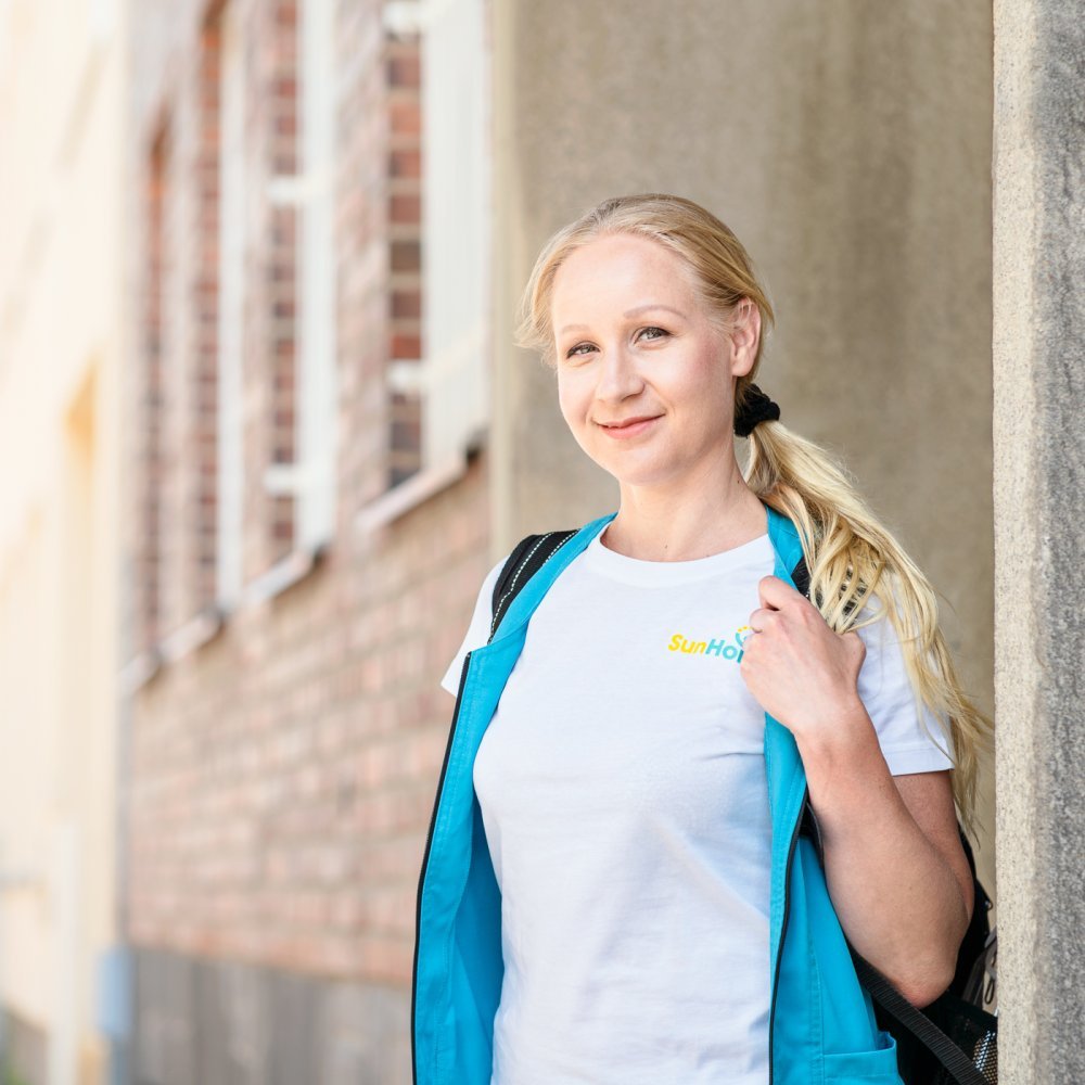 SunHoivan hoitaja seisoo talon edessä ja hymyilee