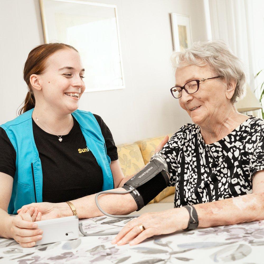 Hoitaja mittaa ikäihmisen verenpainetta